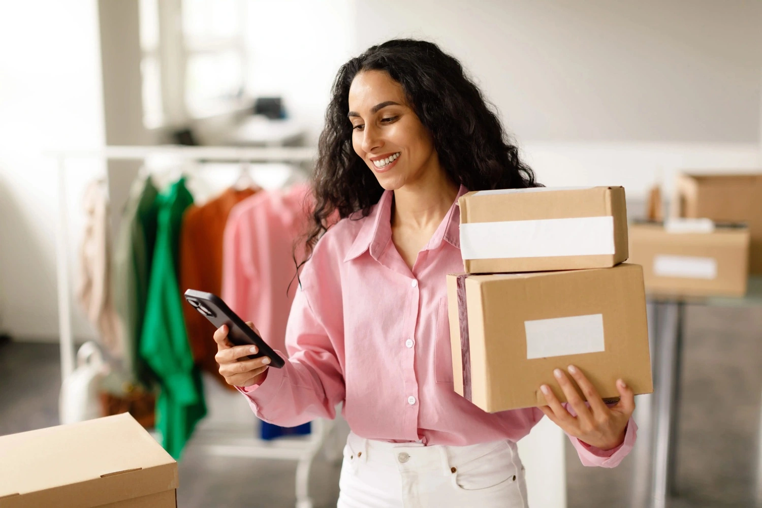 Clothing,Shop,Entrepreneurship.,Happy,Lady,Using,Smartphone,Holding,Packed,Cardboard